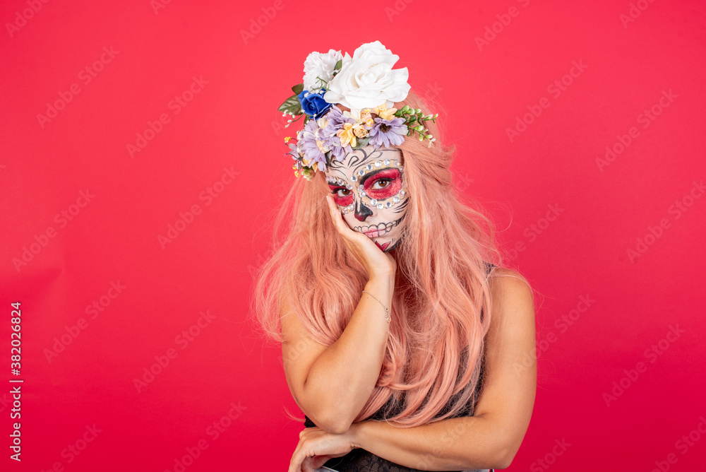 Very bored young beautiful woman wearing halloween make up over red background holding hand on cheek while support it with another crossed hand, looking tired and sick, Very bored young beautiful woman wearing halloween make up over red background holding hand on cheek while support it with another crossed hand, looking tired and sick,