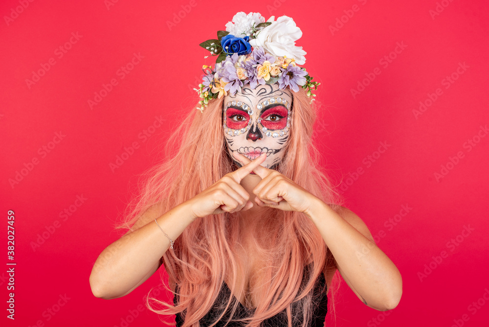young beautiful woman wearing halloween make up over red background standing against yellow wall. Has rejection angry expression crossing fingers doing negative sign. young beautiful woman wearing halloween make up over red background standing against yellow wall. Has rejection angry expression crossing fingers doing negative sign.