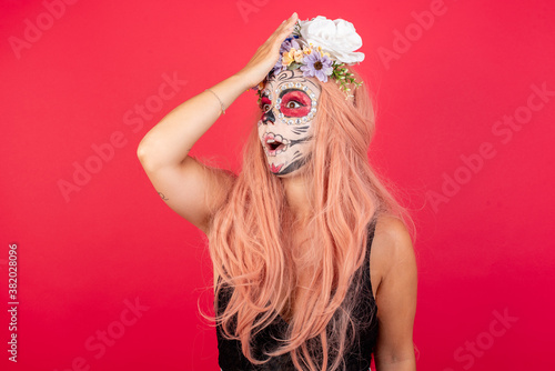Bilde på lerret young beautiful woman wearing halloween make up over red studio surprised with hand on head for mistake, remember error