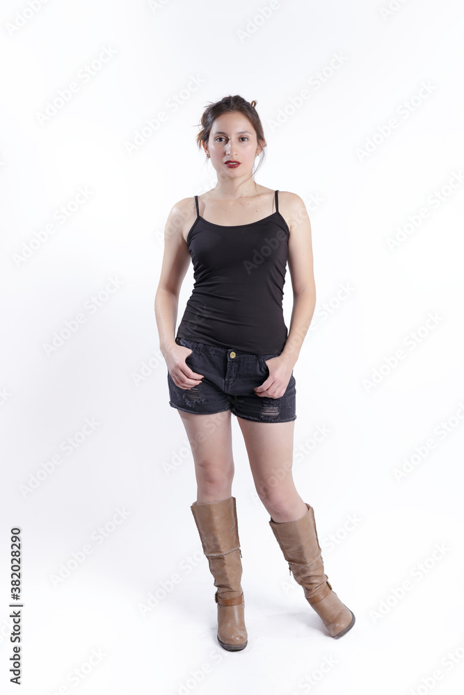 Fototapeta premium A fashion woman wearing top, short and boots posing in a white studio