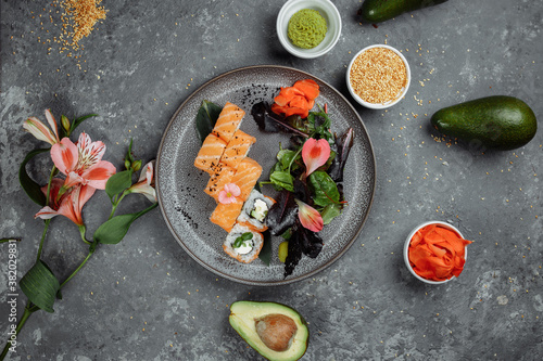 Delicious fresh sushi rolls with salmon and philadelphia cheese on gray plate on dark stone background. Traditional japanese seafood, healthy food concept