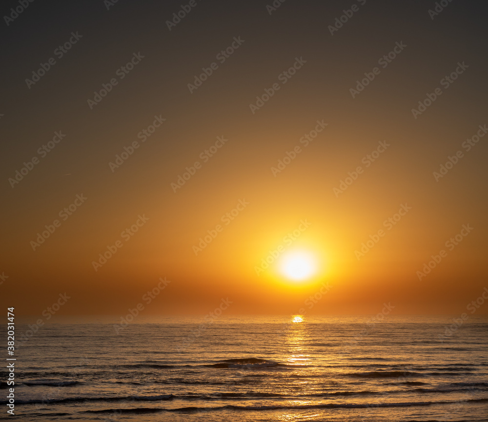 Landscape from calm ocean with golden sun at sunset