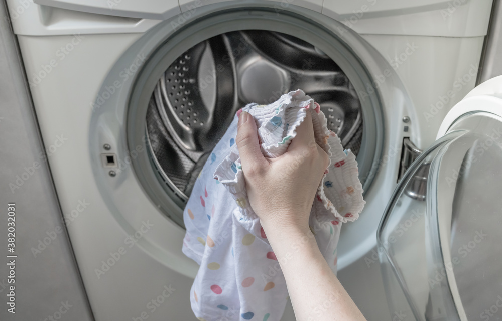 La mano de la mujer blanca pone ropa delicada en la lavadora para lavar la  ropa. foto de Stock | Adobe Stock