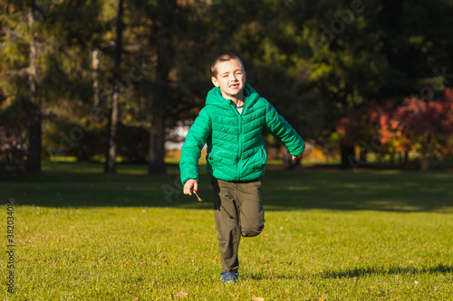 Сheerful boy play fun, run across the green field on a warm autumn day. The concept happy childhood.