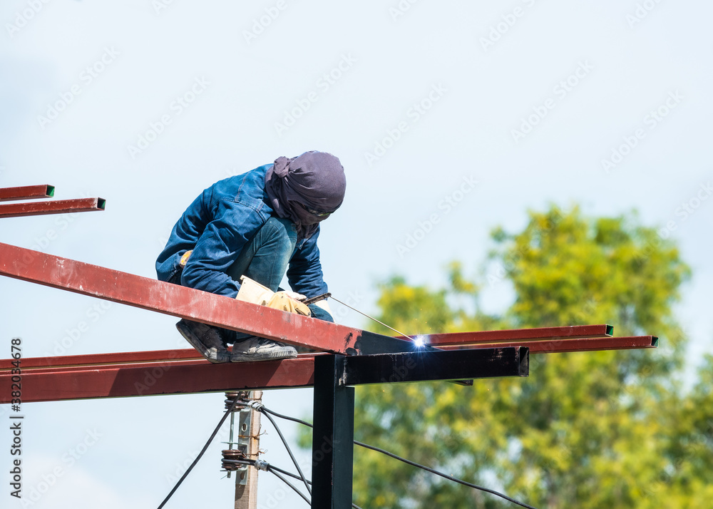 a man works with a welding machine and metal on the roof a man works with a welding machine and metal on the roof