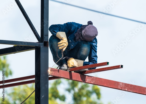 a man works with a welding machine and metal on the roof