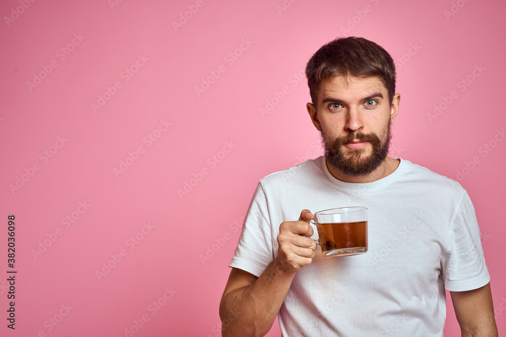 man with a cup of tea on a pink background in a white t-shirt cropped view man with a cup of tea on a pink background in a white t-shirt cropped view