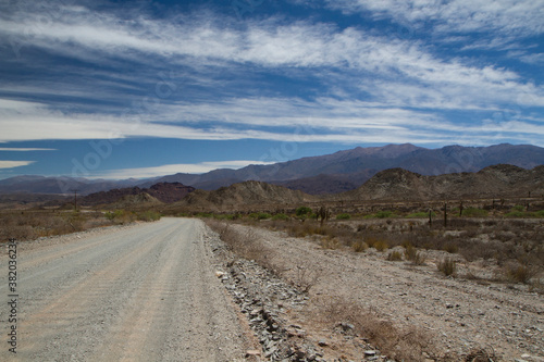 Desert route 40 across the death valley in Salta, Argentina. View of the dirt road, desert and mountains under a beautiful blue sky with clouds.