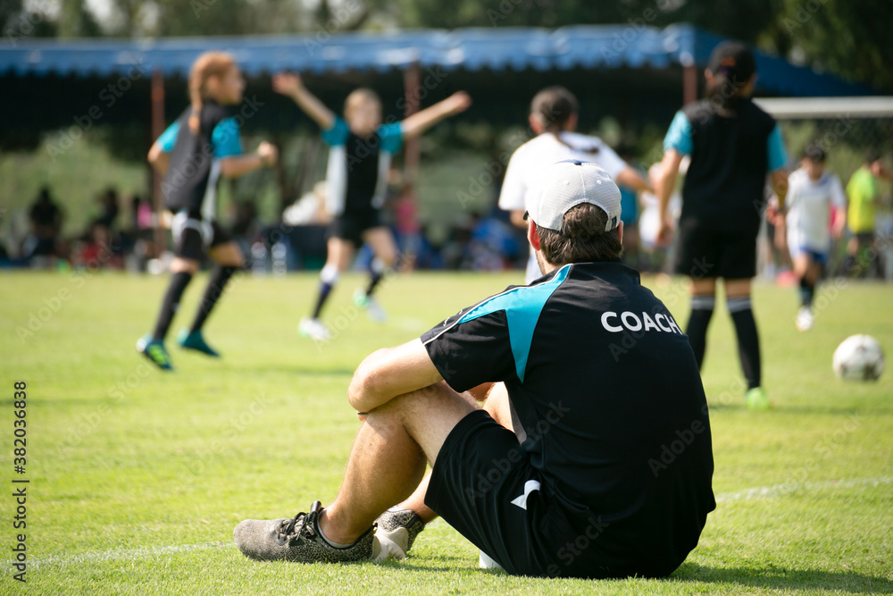Staff coaches who sitting to watch athletes compete on the side of the field. Rear view. Staff coaches who sitting to watch athletes compete on the side of the field. Rear view.