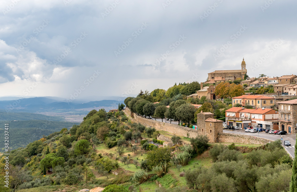 View of the Montalcino Cathedral and houses on the hill, fortress wall around the town and surroundings of Montalcino, Tuscany, Italy