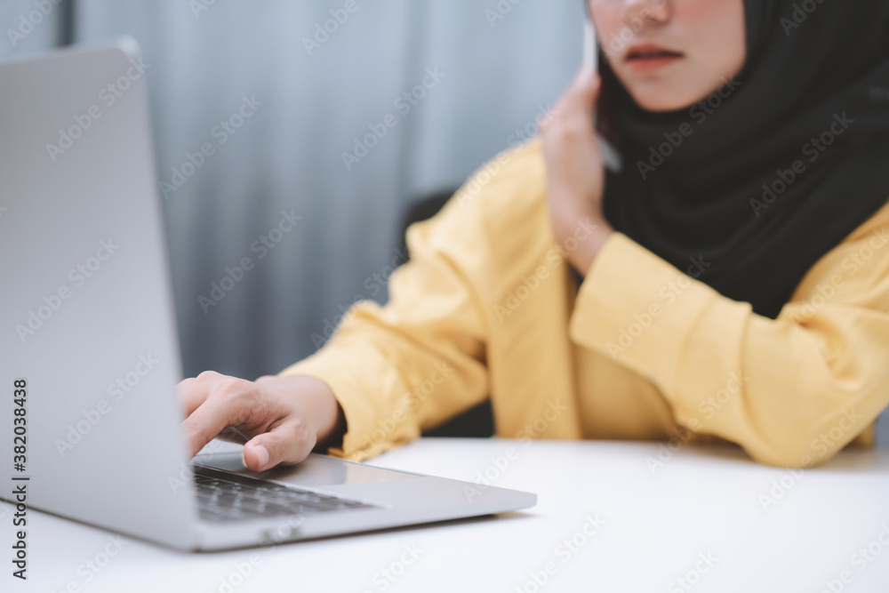 Cropped shot of asian muslim businesswoman working on a laptop computer in office at her home. Working at home concept Cropped shot of asian muslim businesswoman working on a laptop computer in office at her home. Working at home concept