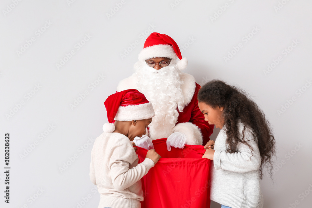 African-American children choosing gifts from Santa's bag on light background African-American children choosing gifts from Santa's bag on light background