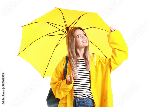 Beautiful young woman in raincoat and with umbrella on white background