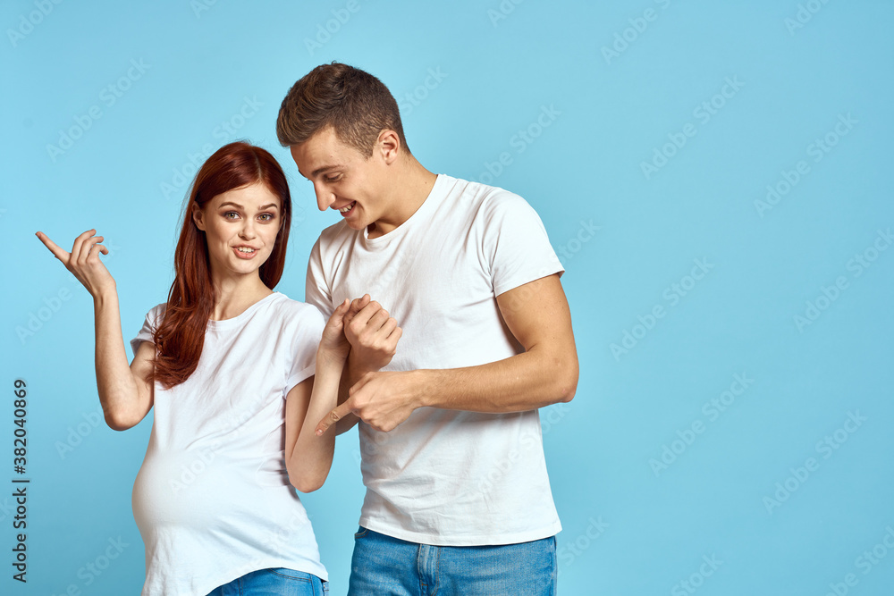 Pregnant woman in white t-shirt and man married couple waiting for baby blue background cropped view of emotions Pregnant woman in white t-shirt and man married couple waiting for baby blue background cropped view of emotions