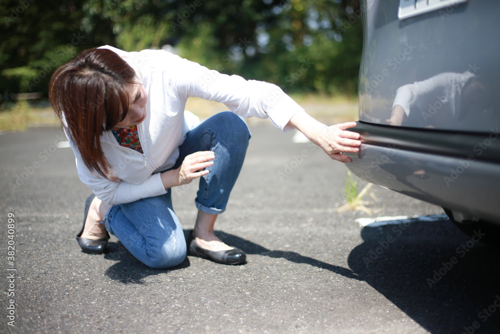 車の傷を確認する女性