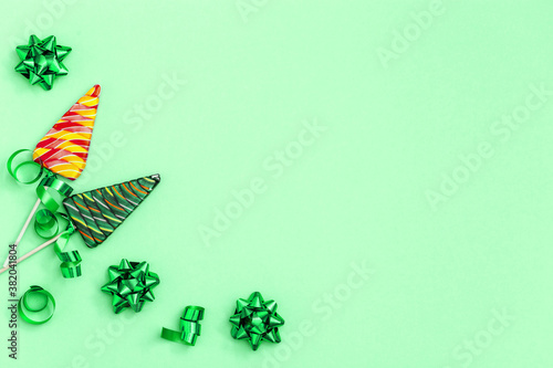 Holiday background with Lollipops shaped like Christmas tree. Creative  New Year Flat lay with sweet candy with stripes on stick on neo mint colored paper with copy space. photo