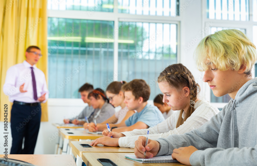 Group of focused teenage students sitting at classroom working at class