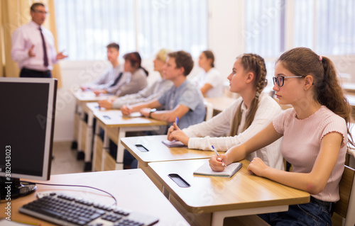 Group of focused teenage students sitting at classroom working at class