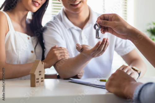 Young couple recieve key for new house or apartment from agency