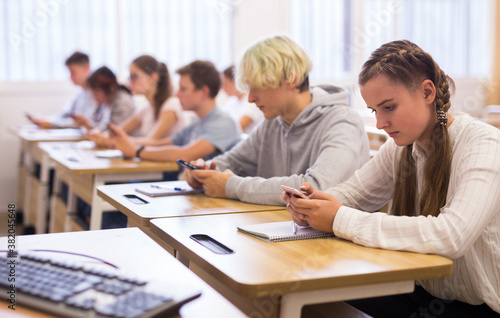 Portrait of teen pupils using mobile phones during lesson © JackF