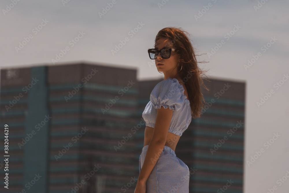 fashionable brunette female stands against high buildings, summer city fashionable brunette female stands against high buildings, summer city