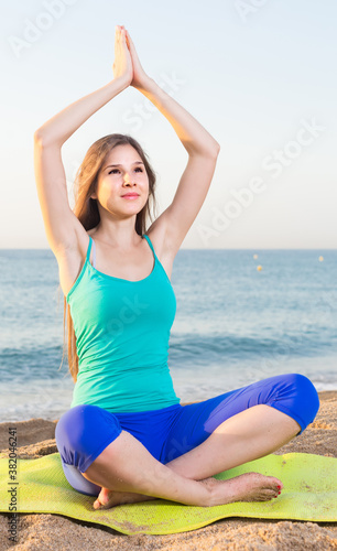 Young woman in blue T-shirt is sitting and practicing asana on nature. © JackF
