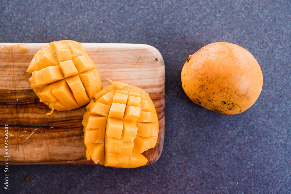 simple food ingredients, sliced mango on cutting board next to another whole mango