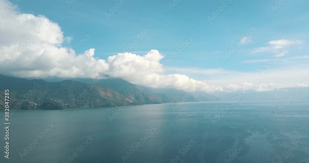 Drone aerial perspective of blue lake atitlan during sunny day with clouds in the mountains in Guatemala. Drone aerial perspective of blue lake atitlan during sunny day with clouds in the mountains in Guatemala.
