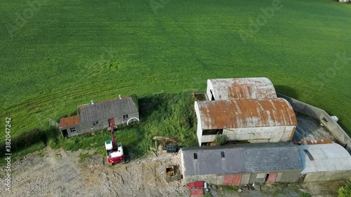 Tilting aerial view of barns and farmhouses in Irish countryside photo