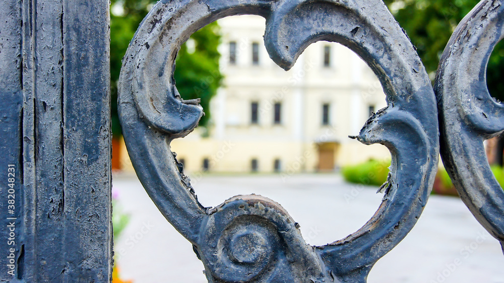 Wrought iron fence with monograms. Peeling paint on metal. Vintage gates to the Park. Wrought iron fence with monograms. Peeling paint on metal. Vintage gates to the Park.