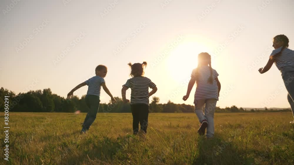 A happy family of children have fun in the park at sunset. Silhouette of fleeing children. Children flee the green lawn in droves. Kids in the park play fun, laugh. Teamwork, playing girls and a boy. A happy family of children have fun in the park at sunset. Silhouette of fleeing children. Children flee the green lawn in droves. Kids in the park play fun, laugh. Teamwork, playing girls and a boy.