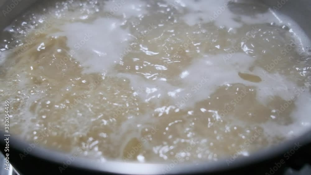 Close up slow motion pasta spaghetti boiling in a steel pot on a gas stove Close up slow motion pasta spaghetti boiling in a steel pot on a gas stove