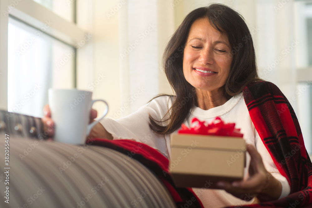 Happy woman holding a gift sitting on the sofa. Happy woman holding a gift sitting on the sofa.