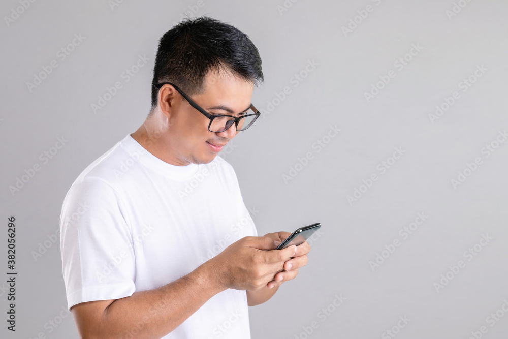 Man typing or chatting on smartphone studio shot on grey background Man typing or chatting on smartphone studio shot on grey background
