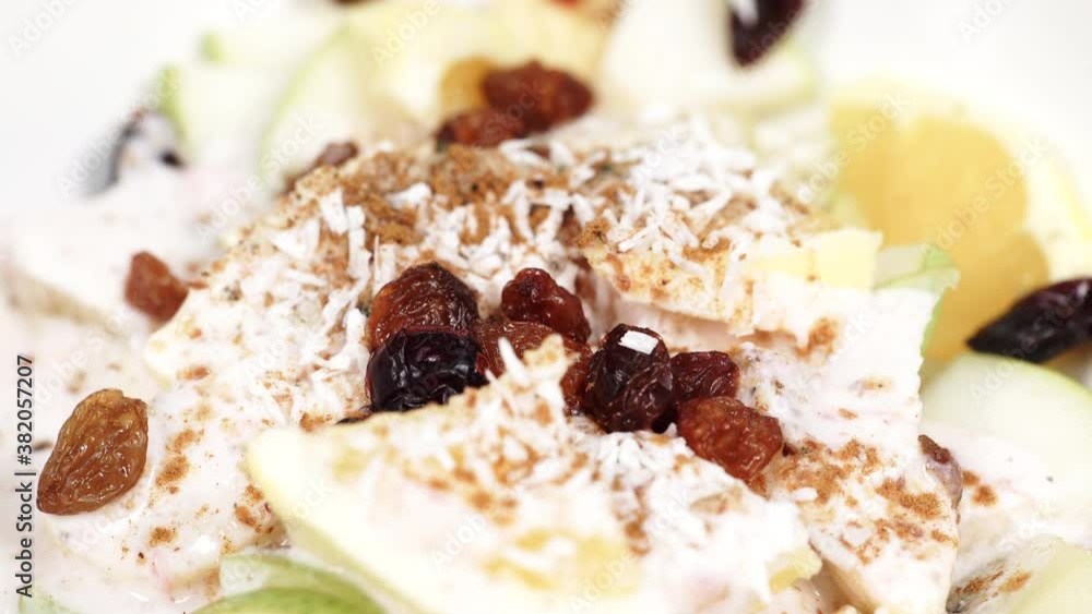 Mixed and assorted fruits in bowl rotating. Healthy salad dessert. Kiwi, orange, pear and banana slices with yoghurt and raisins. Healthy nutrition. Mixed and assorted fruits in bowl rotating. Healthy salad dessert. Kiwi, orange, pear and banana slices with yoghurt and raisins. Healthy nutrition.