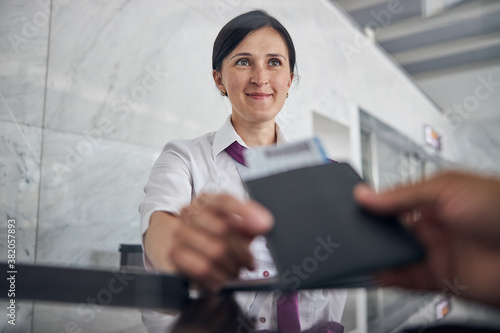 Smiling woman helping passenger with checking in at airport