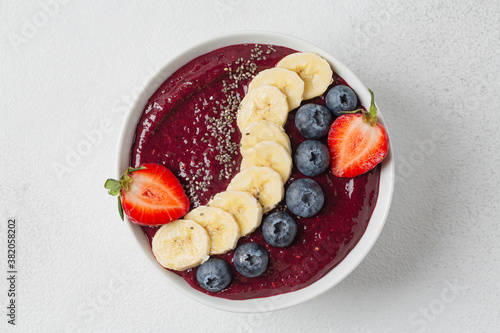 Blueberry smoothie, banana, chia seeds, fresh strawberries in bowl. Eating healthy breakfast bowl. Clean eating, dieting, detox, vegetarian, vegan food concept.