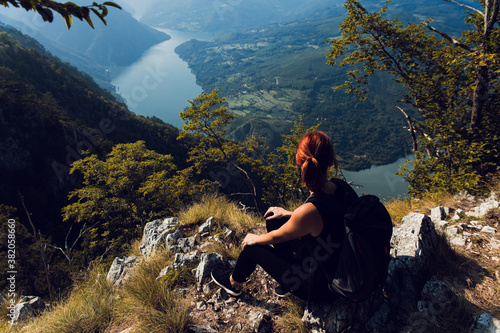 Female hiker with backpack sitting on top of the mountain enjoying the view during the day.