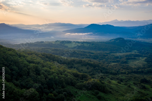 Early morning in the mountains. Morning sun and haze in the valley against the background of mountains. Mountain summer landscape