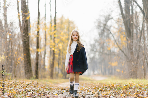 Child on a walk in the autumn park. Preschool girl on the street