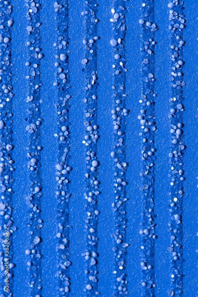 Abstract blue background with textured splashes of small particles, pebbles and glitter, vertical stripes.