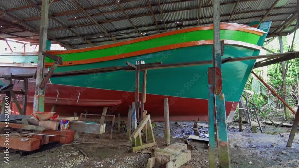 Pan left view of a traditional wooden boat under construction from bow side in Kuala Terengganu, Terengganu, Malaysia. Welding sparks can be seen towards the end of the clip.