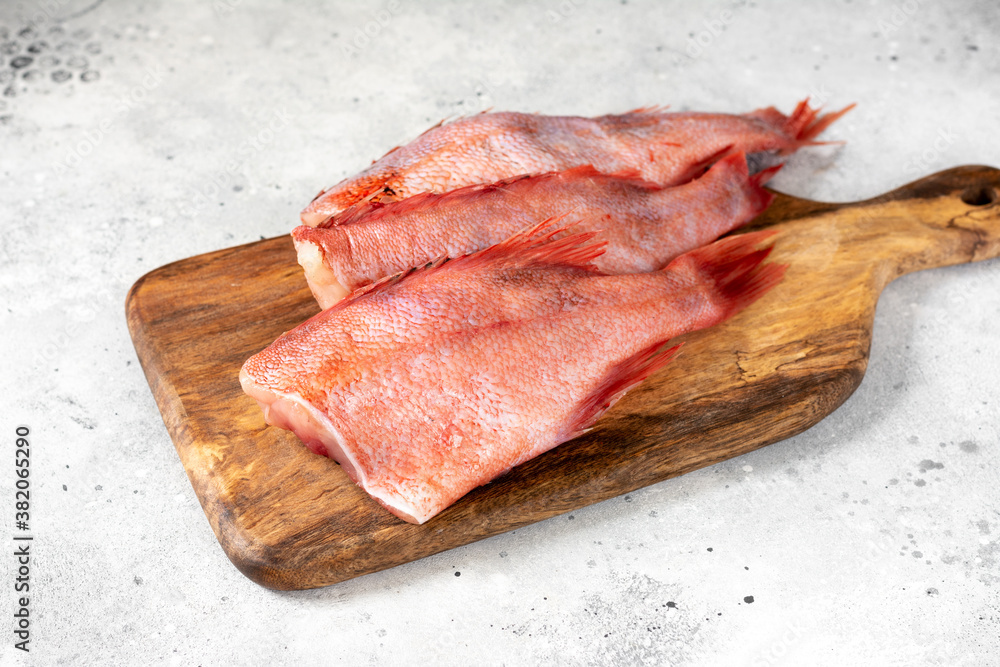 Grouper. Sea bass on a wooden Board on a light gray kitchen table. Raw sea bass closeup