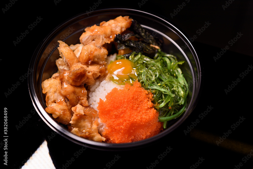 Korean fried chicken dressed with spawn and Seaweed served in a black bow plastic. Korean fried chicken dressed with spawn and Seaweed served in a black bow plastic.
