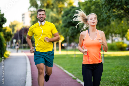 Fototapeta Naklejka Na Ścianę i Meble -  Young couple is jogging on running track in park.