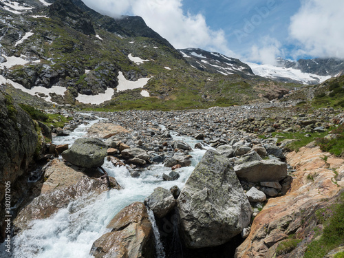 Summer view of alpine landscape with snow-capped mountain peaks and wild Freigerbach stream. Tyrol, Stubai Alps, Austria photo