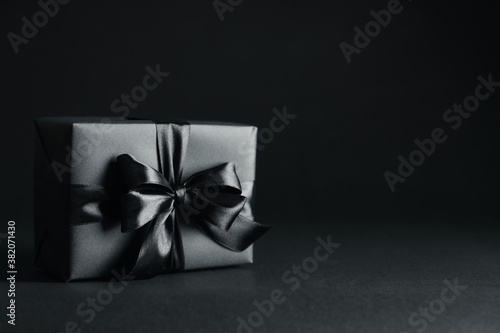 Gift box with black bow on black background