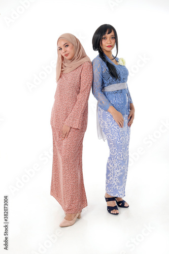 Two South east Asian Malay race ethnic origin woman wearing dress costume kebaya and baju kurung tuding headscarf on white background photo