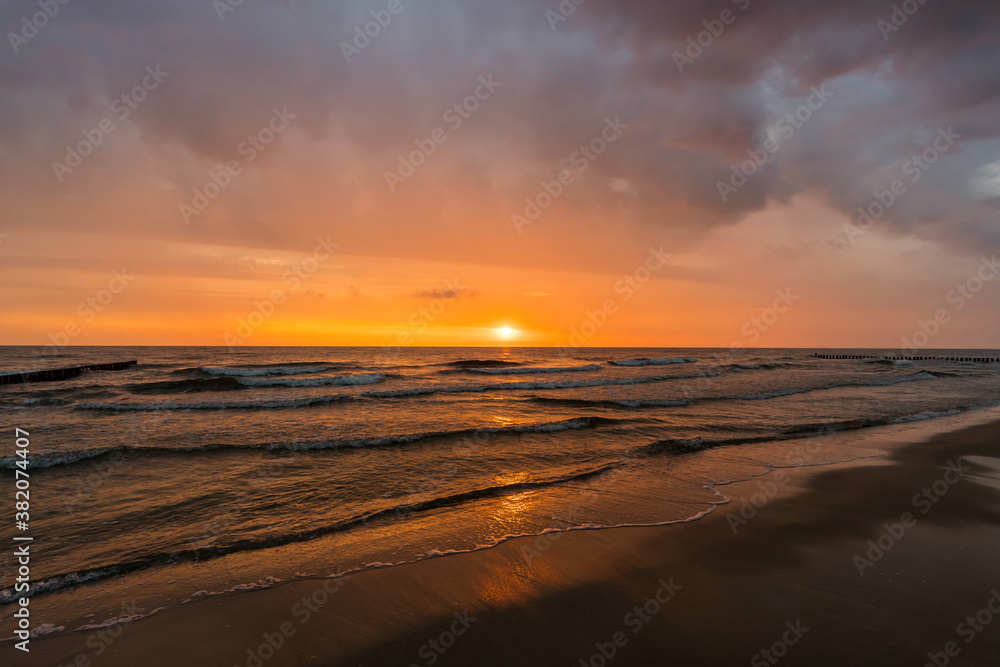 Waves at a beach sunrise with dramatic sky