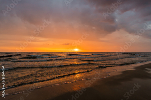 Waves at a beach sunrise with dramatic sky